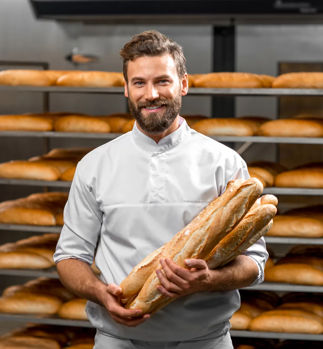 Padeiro sorrindo com baguetes recém-saídas do forno na padaria