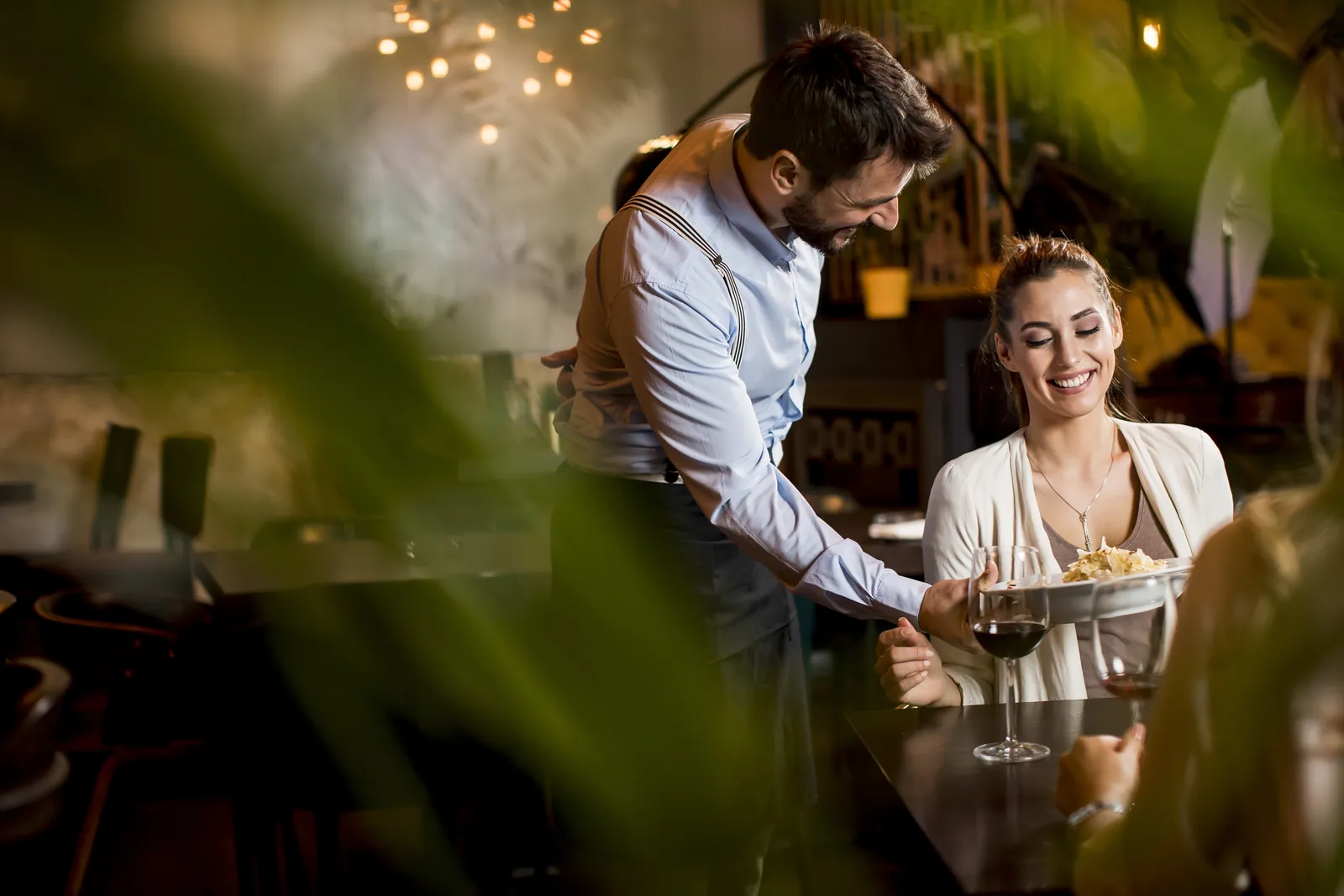 Garçom servindo o prato para uma cliente em restaurante