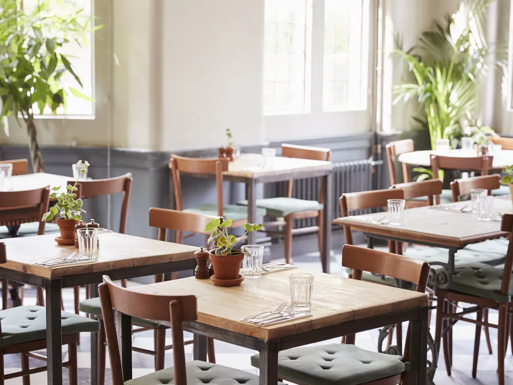 Salão de restaurante com mesas postas e luz natural